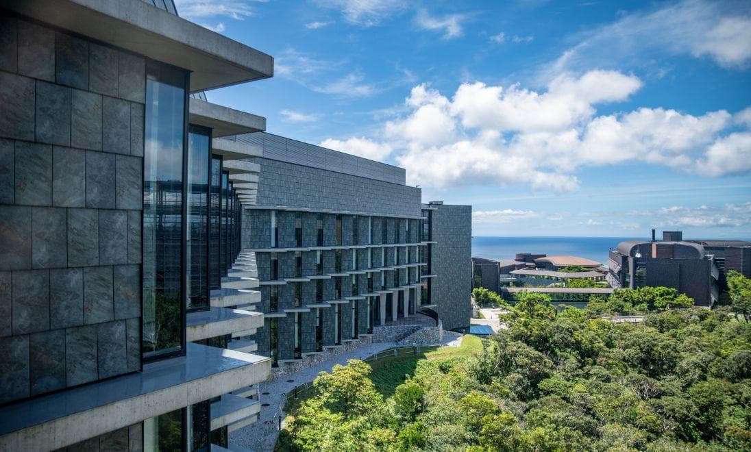 The lab building in left foreground with trees on the right and the sea in the distance.